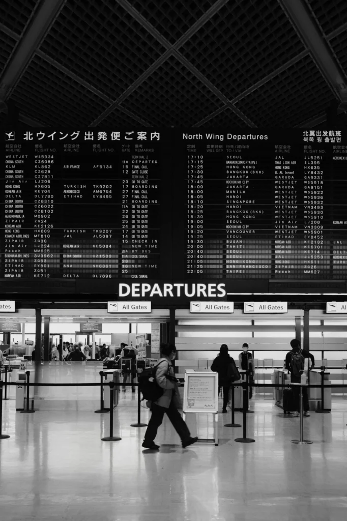 Travellers walking past airport departure information boards